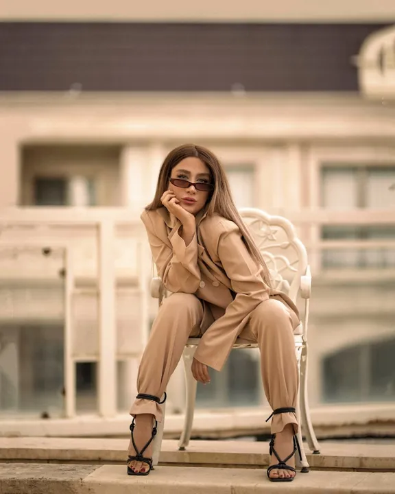 Žena v elegantním béžovém kostýmu se slunečními brýlemi